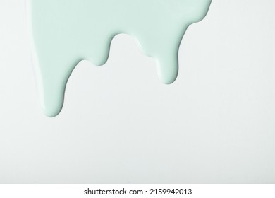 Light cyan liquid drops of paint color flow down on isolated white background. Abstract green backdrop with fluid drip pattern. Acrylic painting with copy space.
