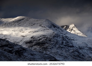 Light dancing on snow-covered Scottish hills. Dramatic, stormy sky. Cluanie, Highlands, Scotland - Powered by Shutterstock