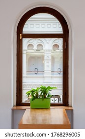 Light Dining Room With Half Circle Wood Window With Table And Green Flowers On The Windowsill