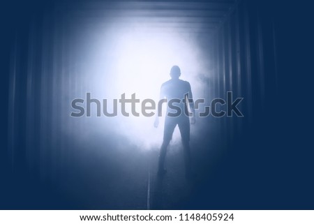 Light at the end of the tunnel. Silhouette of person in underground corridor