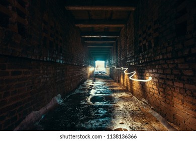 Light and exit in end of dark long brick abandoned industrial tunnel or corridor or sewer channel, way to freedom concept, toned