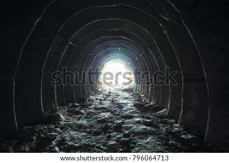 Light and exit in the end of dark long tunnel or corridor, way to freedom concept. Industrial round chalk mine passage with hole, perspective, toned