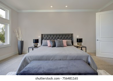 Light Filled Bedroom Showcases A King Size Bed With Tufted Headboard Dressed In Grey Bedding And A Dark Blue Velvet Bench Placed On A White Fluffy Rug. Northwest, USA