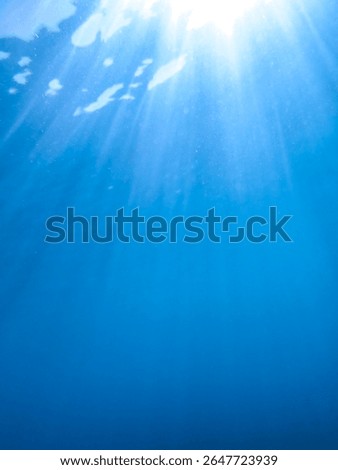 Light filtering down through blue water. Underwater sunlight in deep sea. Light viewed from blue abyss. Underwater sunlight shining deep under water with ripples on wave surface ocean ray, Background.