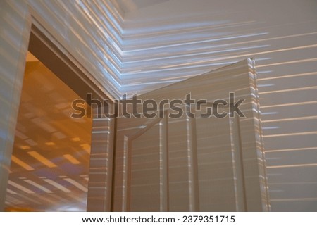Light filters through the window blinds, casting captivating shadows and illuminating empty apartment walls, creating a serene and magical ambiance at night