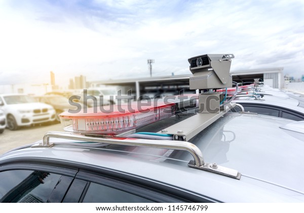 Light flasher with CCTV camera atop of a\
police car an advanced surveillance and security from the illegal\
on blurred of downtown\
background.