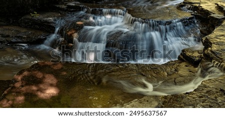 Light funneling through trees creates discs of light on a two sided falls, Enfield Gorge, Robert Treeman State Park, Tompkins County, New York