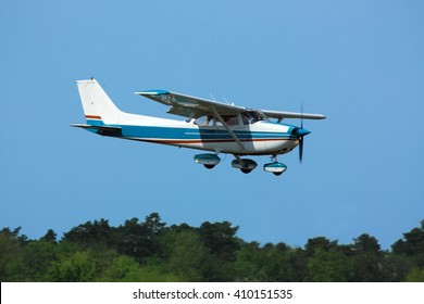 Light General Aviation  Plane On Final Over Green Trees