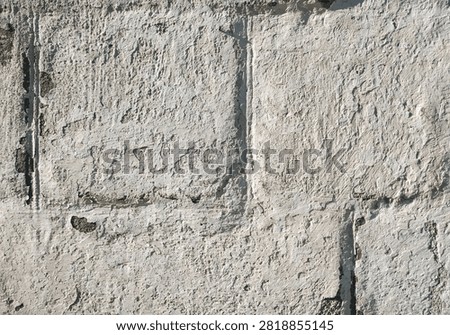 Light gray, almost white cinder block wall covered with lime chalk water-based paint. Old stone surface texture. Close-up.