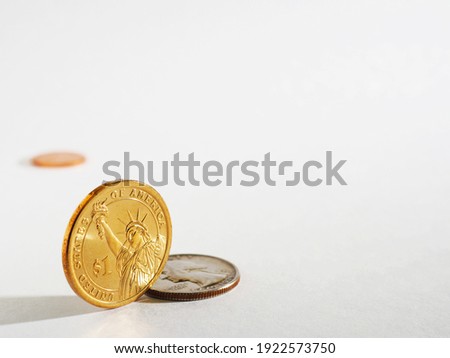 Light gray background on the theme of USA economy, finance and banks with space for text. An American 1 one dollar coin stands on its edge. US coins backdrop with copy-space. Macro