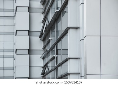 Light Gray Facade Of A Large Building, Geometric Shapes In Architecture, Building Corner, Diagonals, Straight Lines, Windows, Reflection On Glass