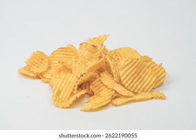 Light gray surface with scattered golden-yellow potato chips of varying sizes Indoor setting, artificial lighting