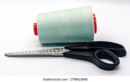 Light green bobbin thread and black scissors isolated on white background. Close up of a spool of light green sewing thread. Thread is a type of yarn but similarly used for sewing.  - Shutterstock ID 1798423840