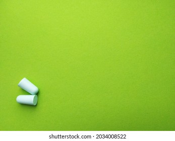 Light green earplugs on a green background - Shutterstock ID 2034008522