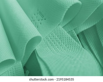 Light Green Polypropylene Bag. Non-woven Fabric With Wavy Pleats. Pile Of Environmentally Friendly Bag Materials. Spunbond Bag