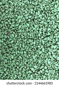 Light green rubber playground cover. Granular soil texture close-up.
