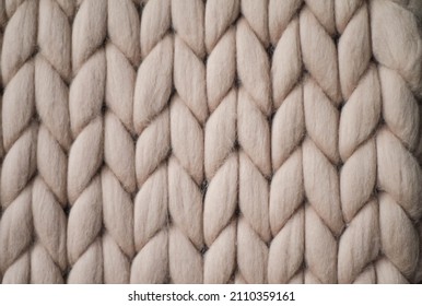 Light grey knitted background. Woolen fabric with pattern of braids. Neutral background of drawing.	