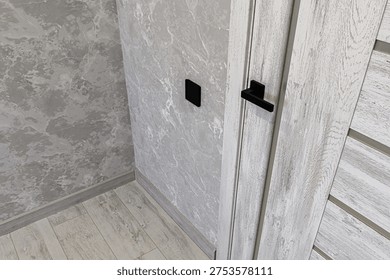 Light grey marble-patterned interroom door with black handle and switchplate; paired with light wood-textured flooring and matching wall covering in modern neutral palette.