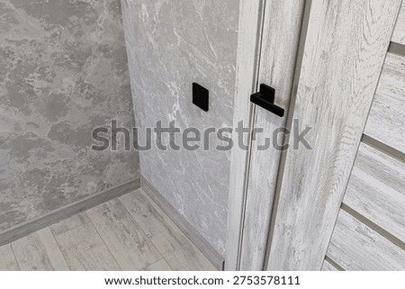 Light grey marble-patterned interroom door with black handle and switchplate; paired with light wood-textured flooring and matching wall covering in modern neutral palette.