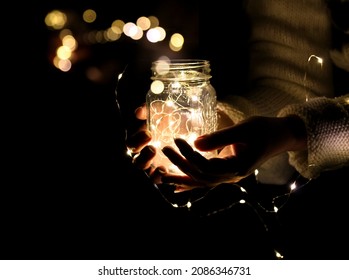 A light in the hands of a man, a photo of a jar with a garland and a bokeh from the lights