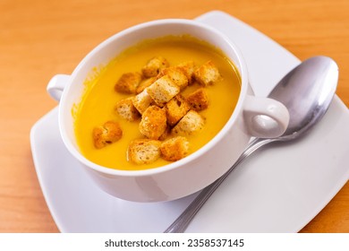 Light healthy carrot cream soup with croutons served in plate. Vegetarian concept. Gastronomic delight..