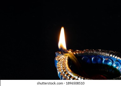 Light Of Hope Or Enlightenment In Dark Theme - Flame Emitting From Blue Color Diya Made Of Clay And Mud Lit On Black Background With Space For Text. Deepak Or Deep Is Used In Deepavali Or Deepawali