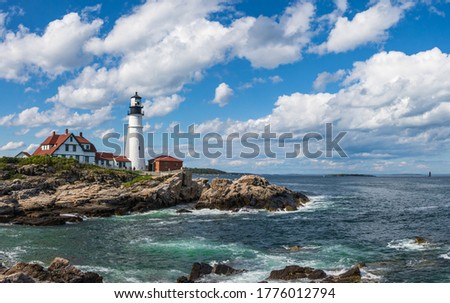 Light house on a rocky sea coast with blue sky backdrop with clouds