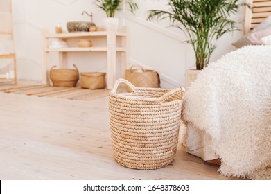 Light interior made of natural eco components. Wicker straw basket for storing clothes and things on the background of the washbasin and bath in the Boho style with wicker baskets and wooden shelves