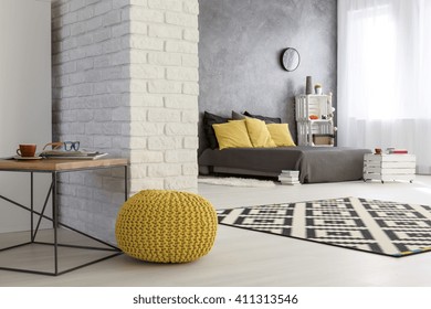 Light interior with white, decorative brick wall, yellow pouffe and spacious bedroom