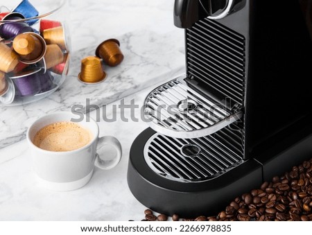 Light kitchen with coffee machine and cup of aroma coffee with capsules pods on white marble board