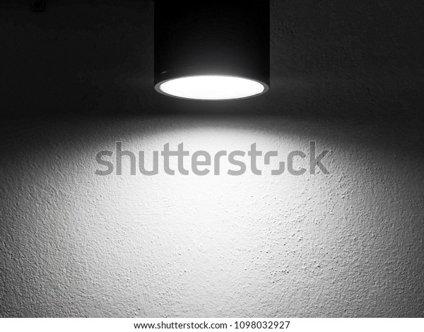 Light of\
lamp on wall at night background. Empty plain wall with naked light\
bulb. Background in a minimalist style. The scattered light bulb\
creates focus on slight relief\
surface.