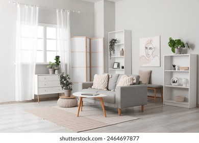 Light living room with folding screen, comfortable sofa, coffee table and chest of drawers