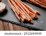 Light meat sticks on board with fresh herbs, garlic, and tomatoes, perfect for food styling needs