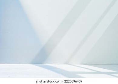 Light minimalist geometric background image in gray and light blue tones with light and shadow from window for product presentation.