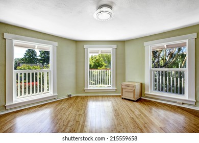 Light mint empty room with three windows and hardwood floor