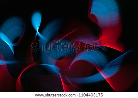 Light painting abstract background. Blue and red light painting photography, long exposure, ripples and swirl against a black background.