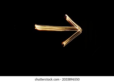 Light Painting Arrow Sign. Drawn Arrow Shape With Gold Lights. Long Exposure Photography.