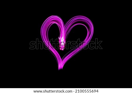 Light painting heart shape. Heart drawn with pink lights against black background. Long exposure photography. February 14 Valentine's Day background photo.