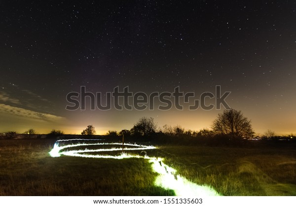 Light\
painting in the landscape with meadow and\
trees