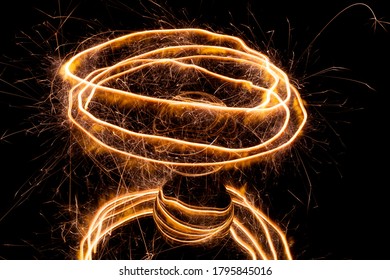 Light Painting With A Sparkler Circling Around A Glass Ball On A Black Backgtound.