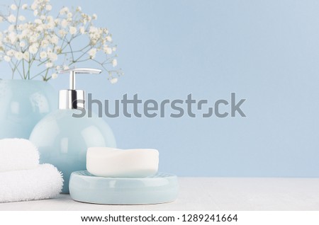 Light pastel blue acessories for bath and skin and body care product - soap, soap dispenser, towel  on white wood table. Decor for bathroom interior.