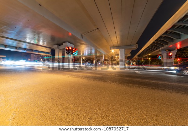 The\
light path of a car under a highway and a\
viaduct.