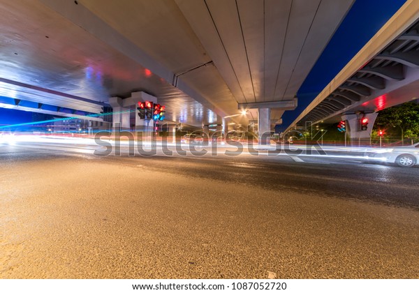 The\
light path of a car under a highway and a\
viaduct.