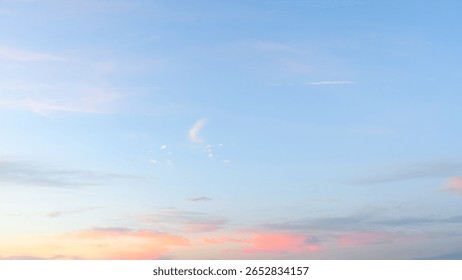 Light pink clouds float near the horizon under a clear blue morning sky during early sunrise.