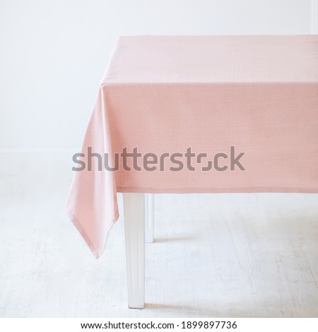 A light pink decorative tablecloth on a table on a white background