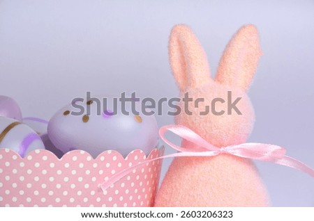 Light pink Easter bunny and purple eggs. Purple background. Easter.