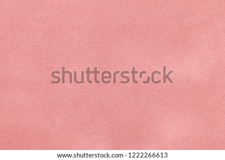 Light pink matte background of suede fabric, closeup. Velvet texture of seamless pastel leather.