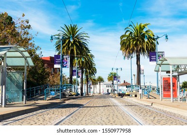 Light rail tracks, empty bus and tram stop passenger shelter with accessible ramp on F Market Wharves light rail lane along palm tree lined Embarcadero boulevard - San Francisco, CA, USA - 2019