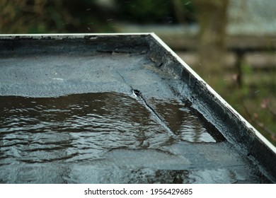 Light Rain On A Black Flat Roof With A Small Leak