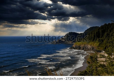 Light rays filter through storm clouds and illuminate the Heceta Head Lighthouse on the Oregon Coast.  